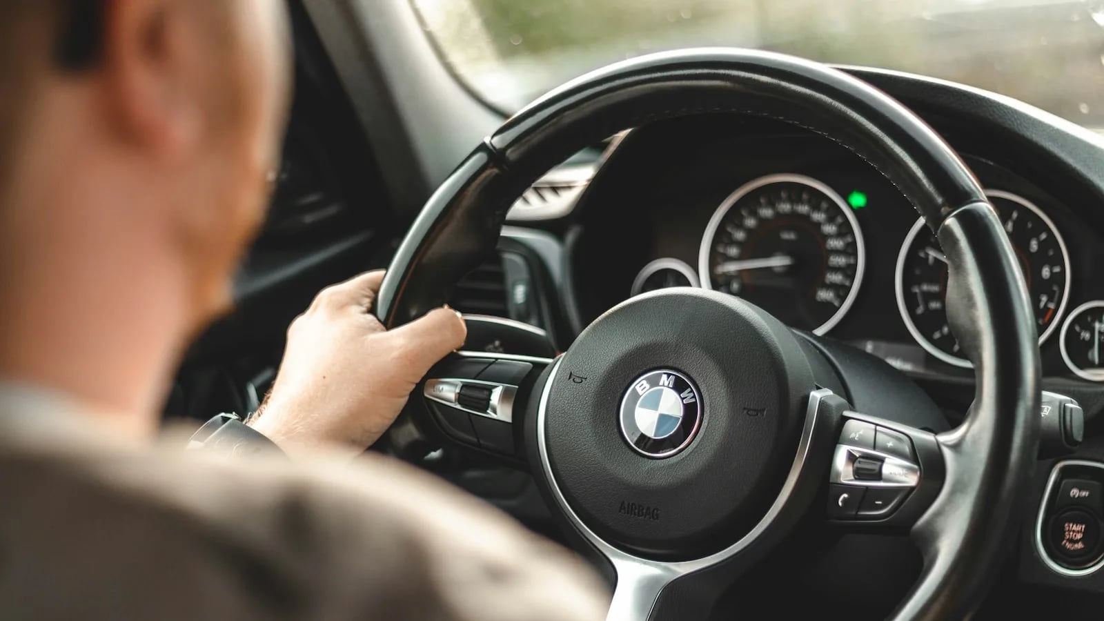 Водитель держит руль BMW, вид со спины