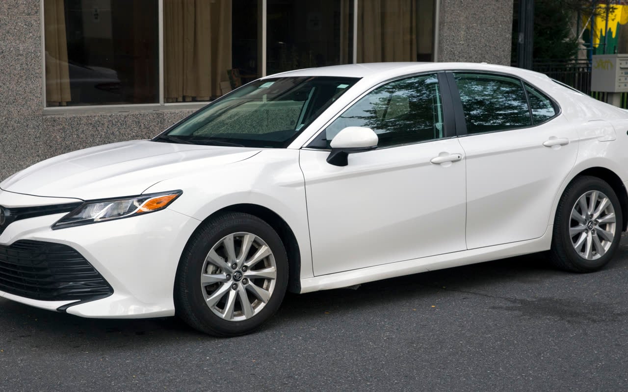 Белый Toyota Camry на улице, вид сбоку