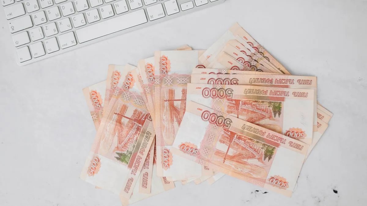 Пачки купюр по 5000 рублей на столе рядом с клавиатурой